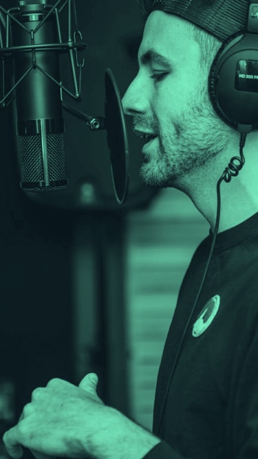a man in a recording studio wearing headphones and speaking into a microphone